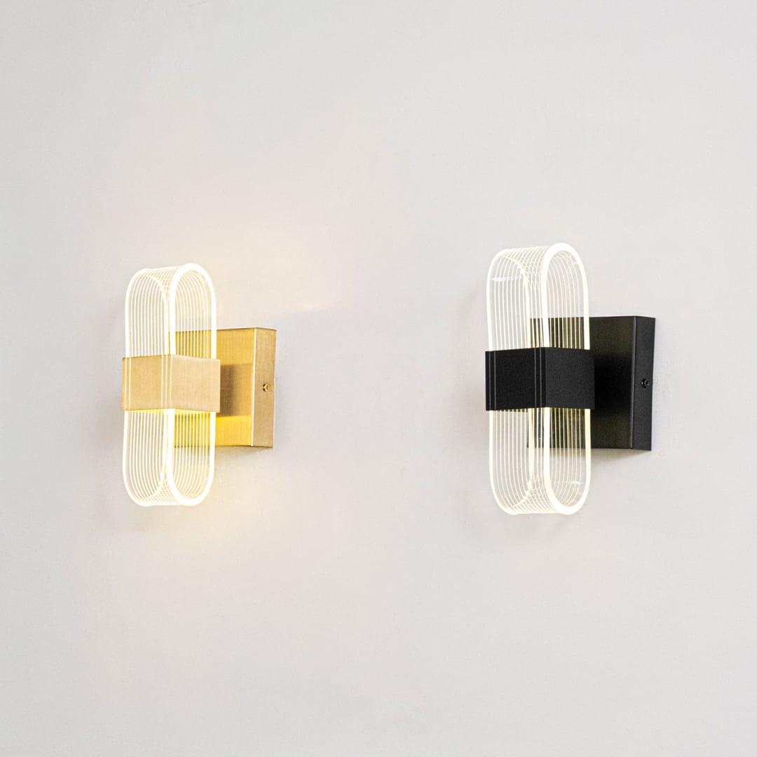 Black metal and ribbed glass wall lights illuminated on a clean white background showing bright warm glow.