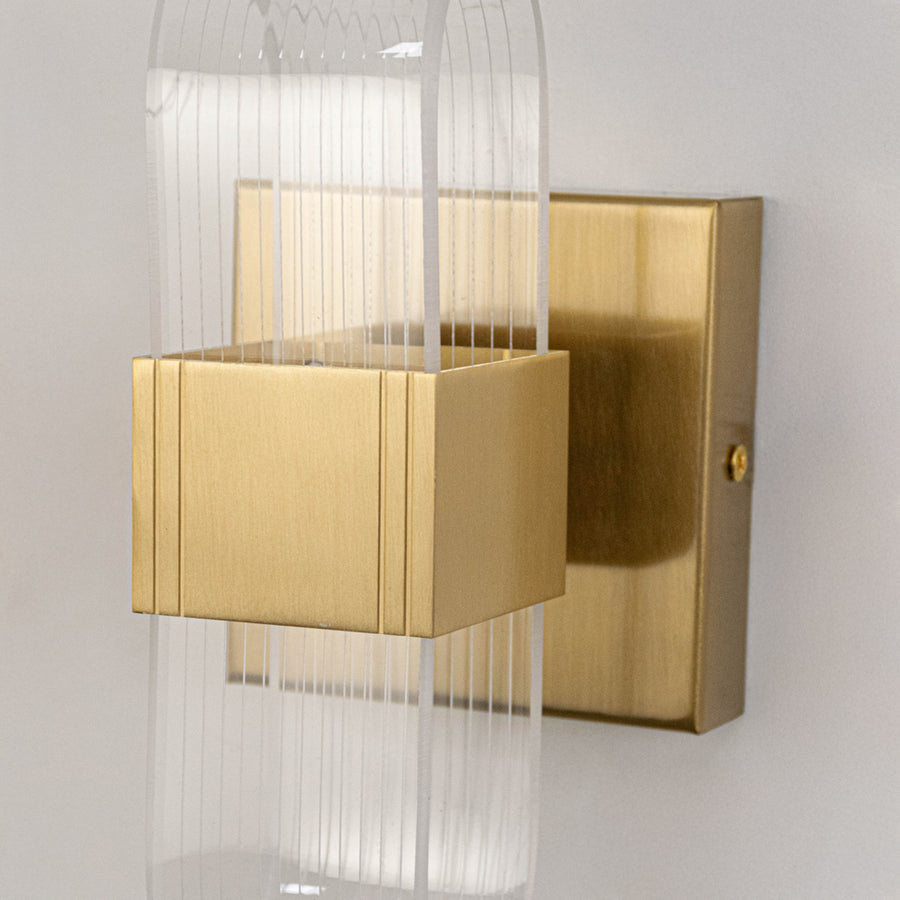 Decorative wall light in gold metal finish with textured glass panels for bedroom or living decor lighting placement white background.