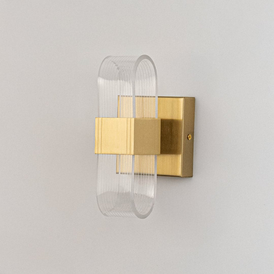 Gold wall light with ribbed clear glass shade shown on a bright white background for accurate product detailing.