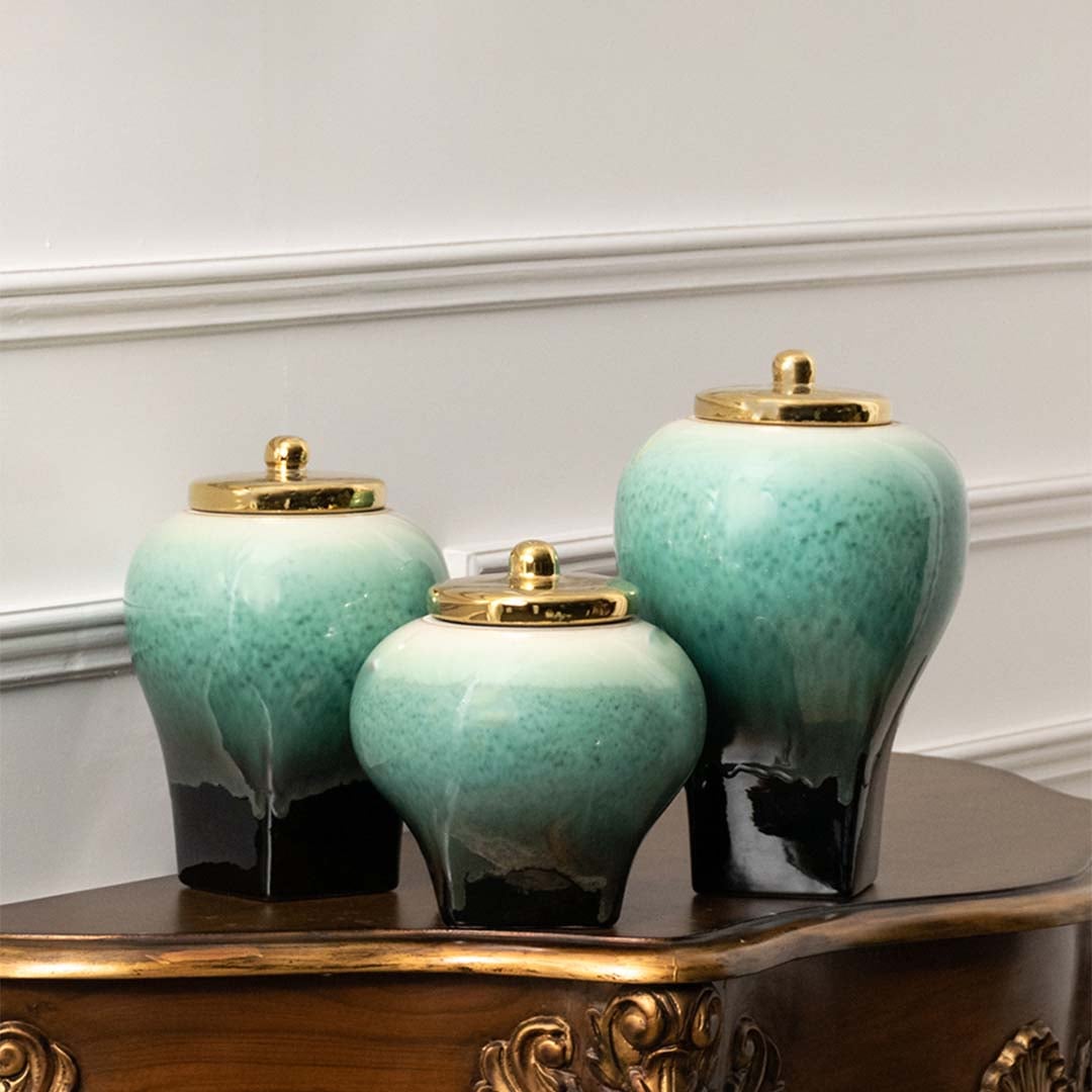 Set of teal ceramic decorative vases with gradient glaze and gold lids arranged together on white background for decor display.