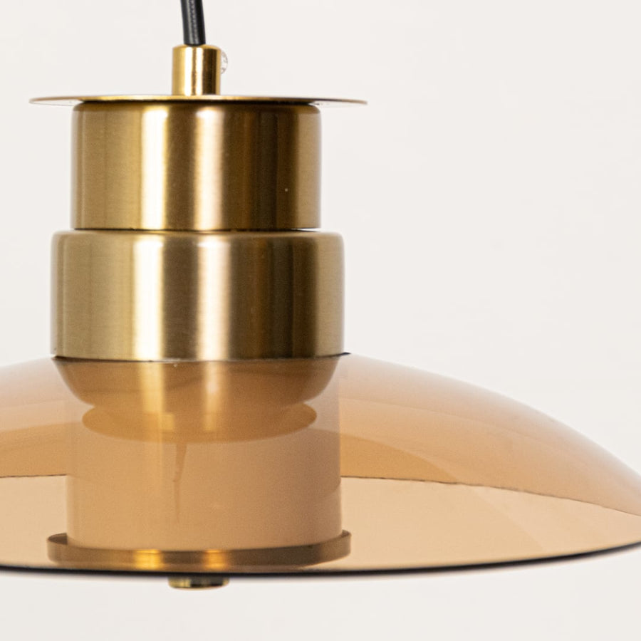 Closeup of amber glass pendant light featuring gold metal detailing showing the smooth glass finish and warm modern style.