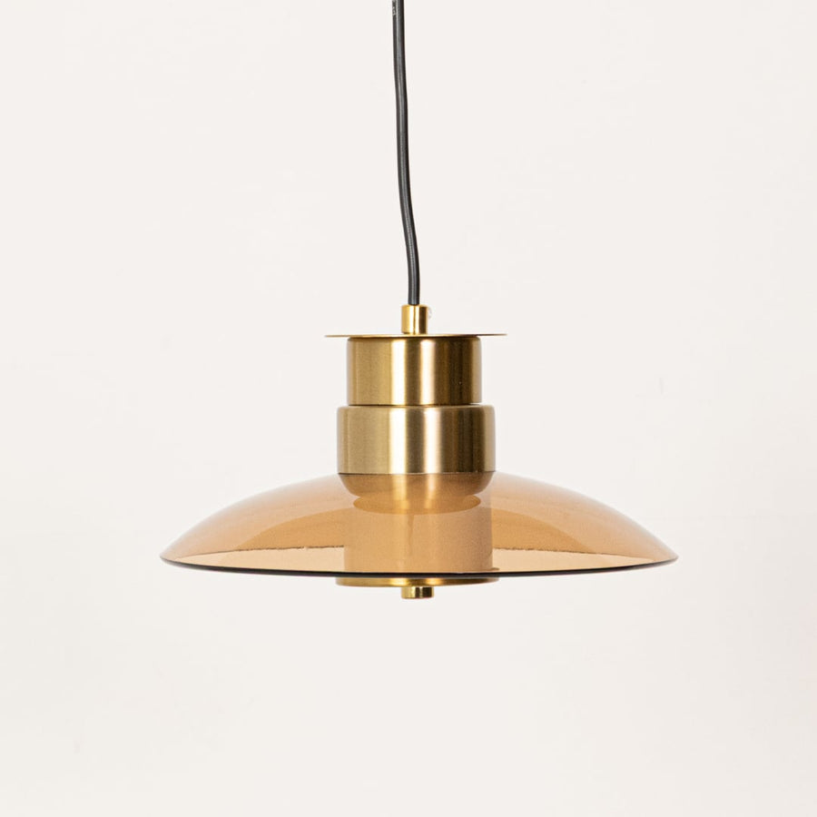 Amber glass pendant light with gold metal detailing displayed with lights off against a clean white background showing its sleek form.