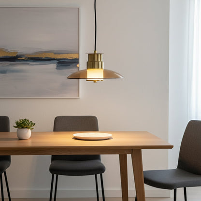 Elegant gold and amber glass pendant light glowing warmly over a modern dining table creating a cozy lifestyle setting with soft ambient lighting.