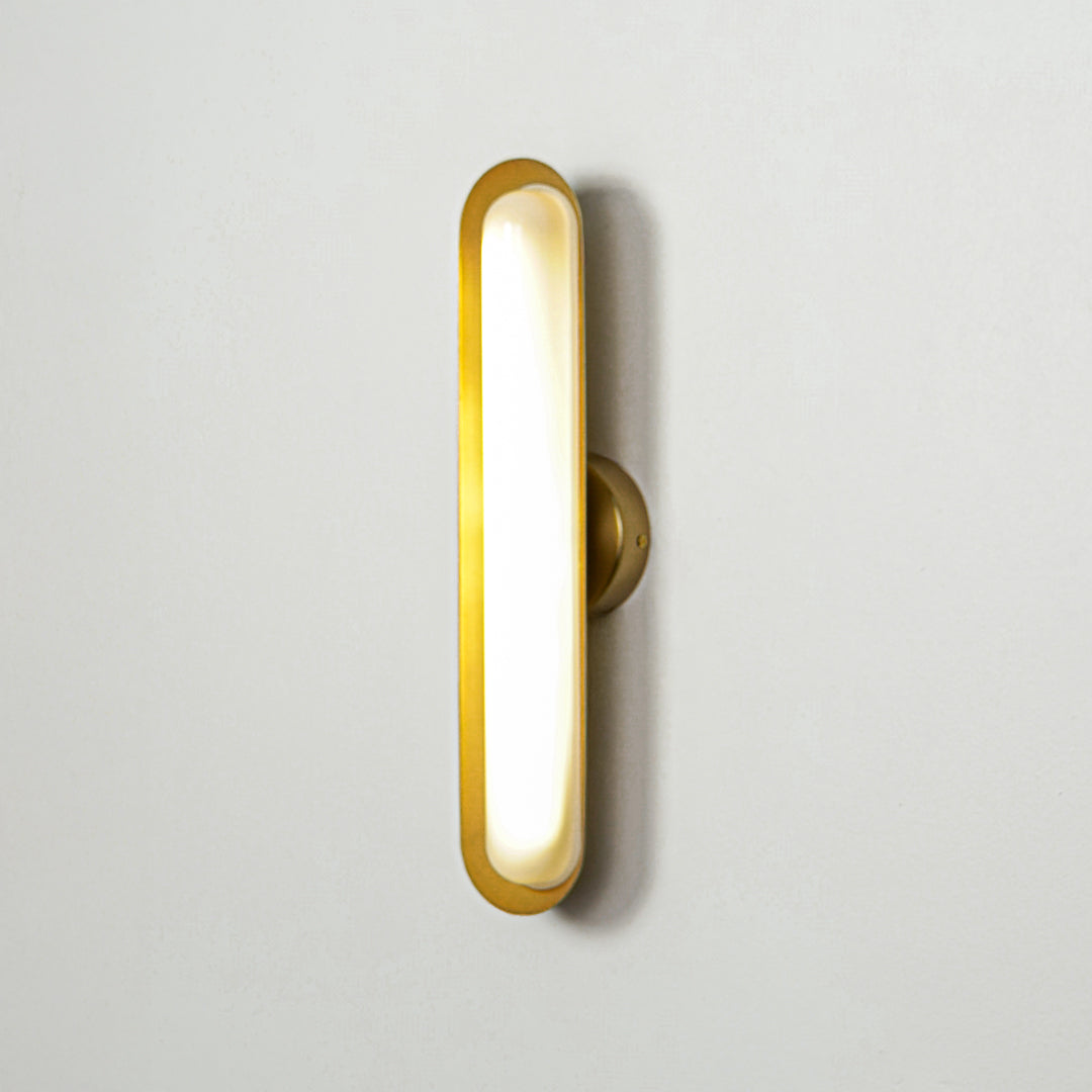 Contemporary gold wall sconce with glowing oval shape on clean wall background ideal for stylish interior accent lighting.