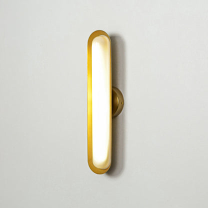 Contemporary gold wall sconce with glowing oval shape on clean wall background ideal for stylish interior accent lighting.