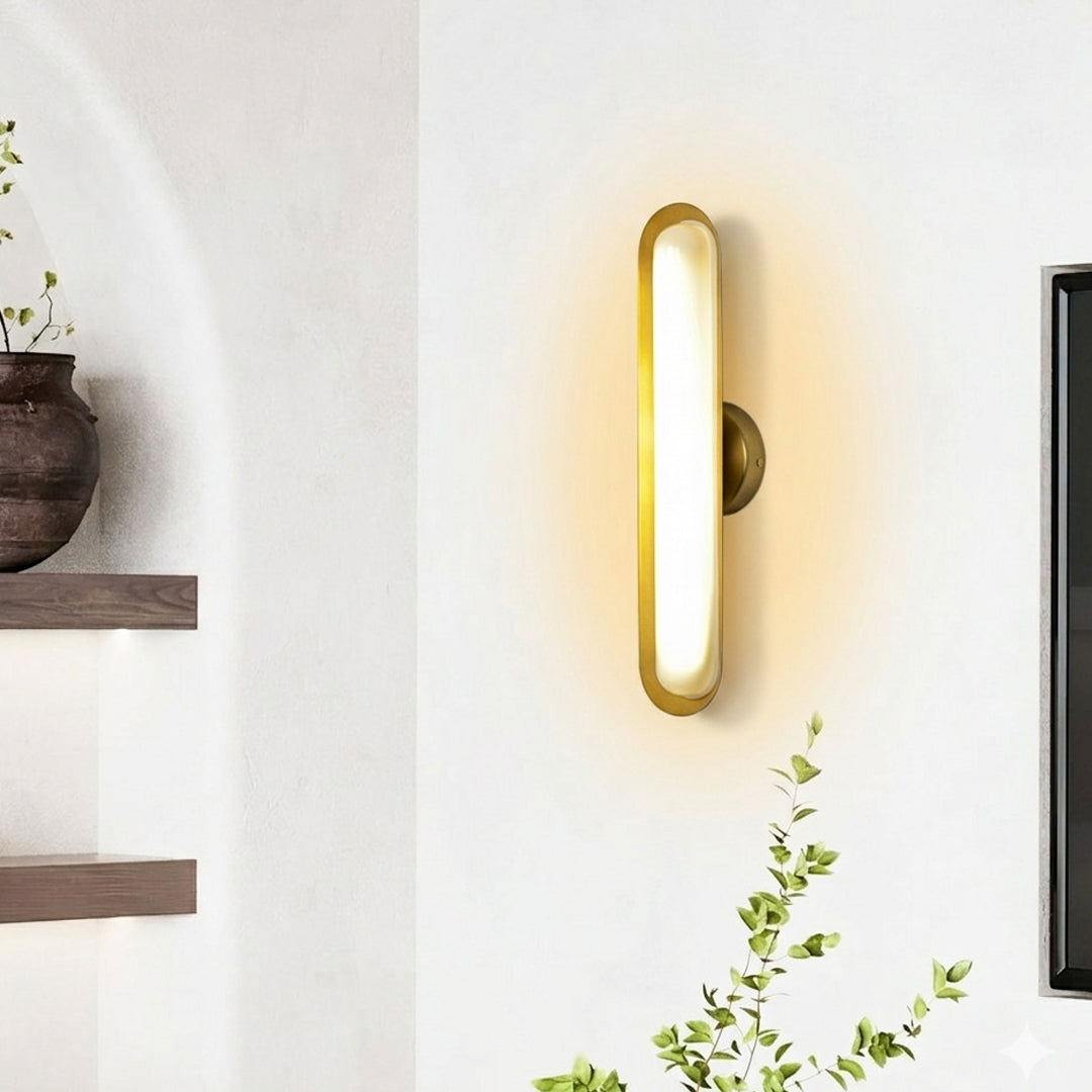 Gold wall light with vertical oval LED design mounted on neutral wall background perfect for modern bedroom or hallway decor lighting.