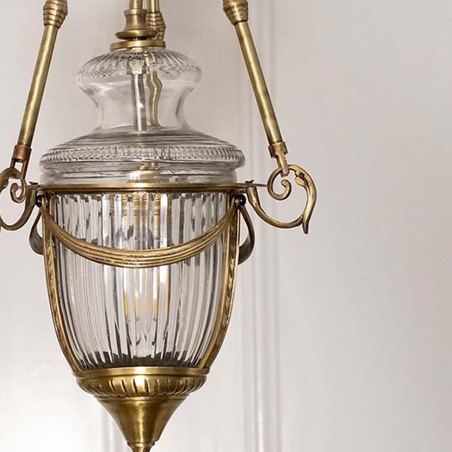Closeup of antique brass and ribbed glass lantern pendant light showcasing intricate vintage craftsmanship.