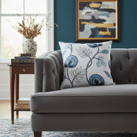 White cotton cushion cover with blue botanical print styled on a modern sofa for elegant living room home decor.