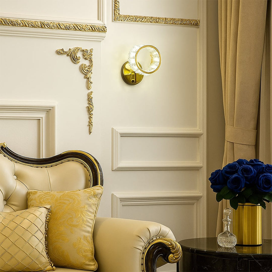 A glass and gold metal wall light measuring 21 cm height and 17 cm width displayed on a smooth white wall with the light off adding modern décor.