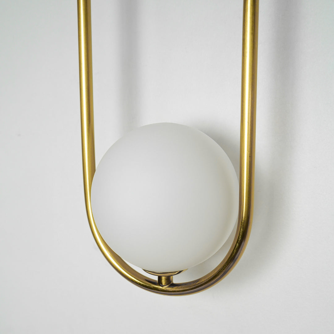 Closeup image of gold metal wall light with frosted globe shade for stylish luxury wall lighting decor.