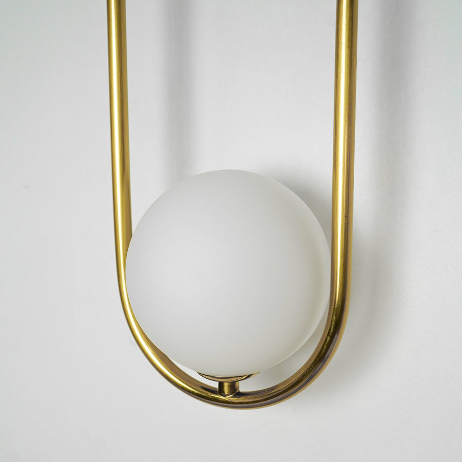 Closeup image of gold metal wall light with frosted globe shade for stylish luxury wall lighting decor.