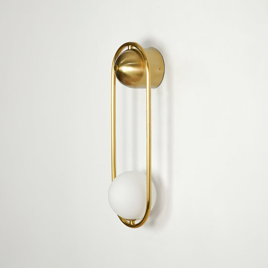 Gold metal wall light on white background with frosted globe shade for elegant modern interior decor.