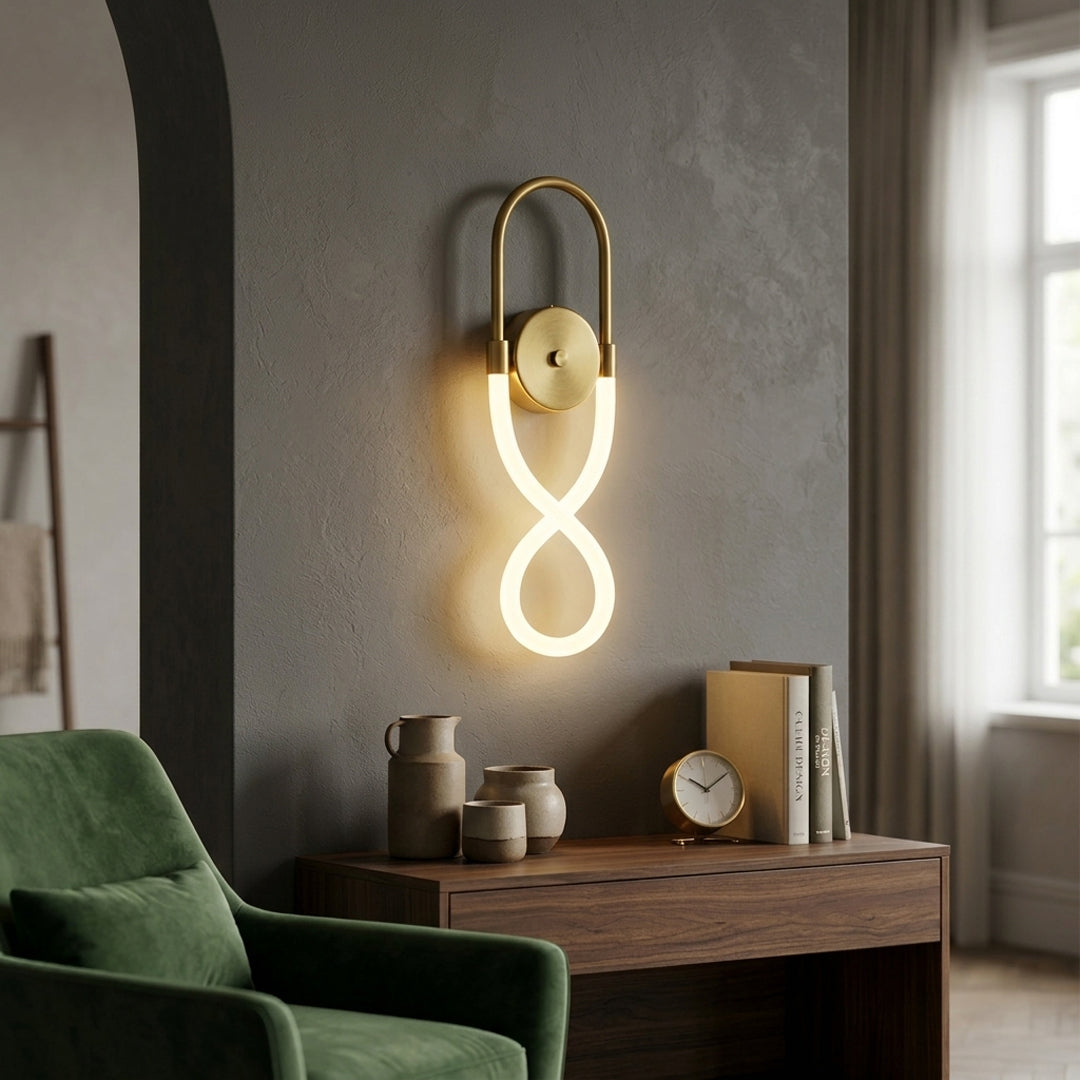 Modern gold wall sconce with infinity loop LED design installed in cozy living room setting perfect for contemporary interior accent lighting.