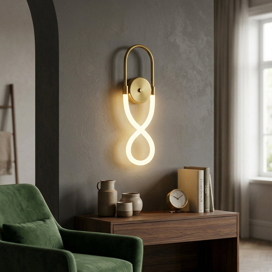 Modern gold wall sconce with infinity loop LED design installed in cozy living room setting perfect for contemporary interior accent lighting.