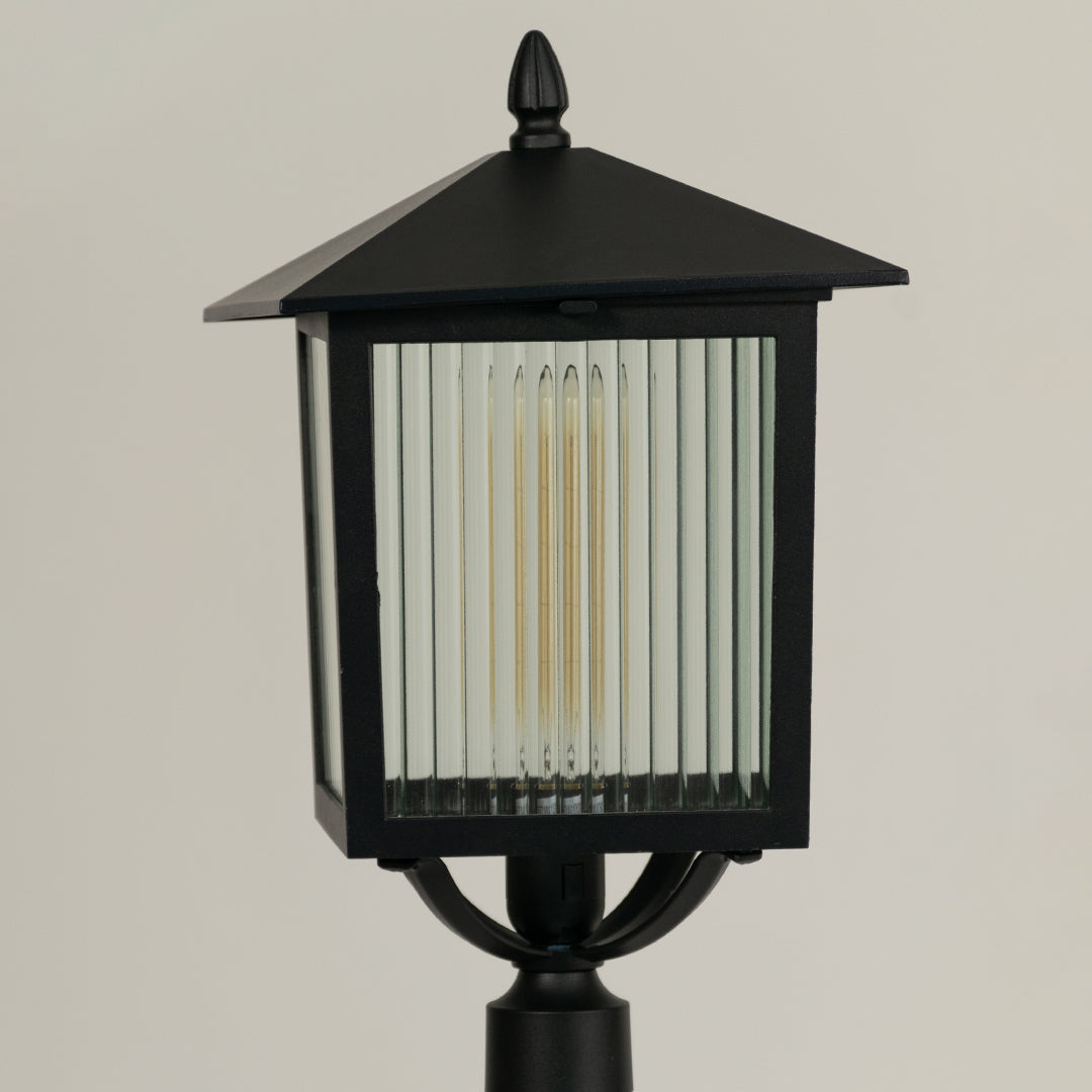 Closeup of black outdoor garden light with ribbed glass panels for elegant exterior decor styling use.