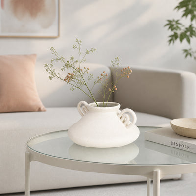 White ceramic flower vase with dried blooms placed on glass table for stylish contemporary home decor.