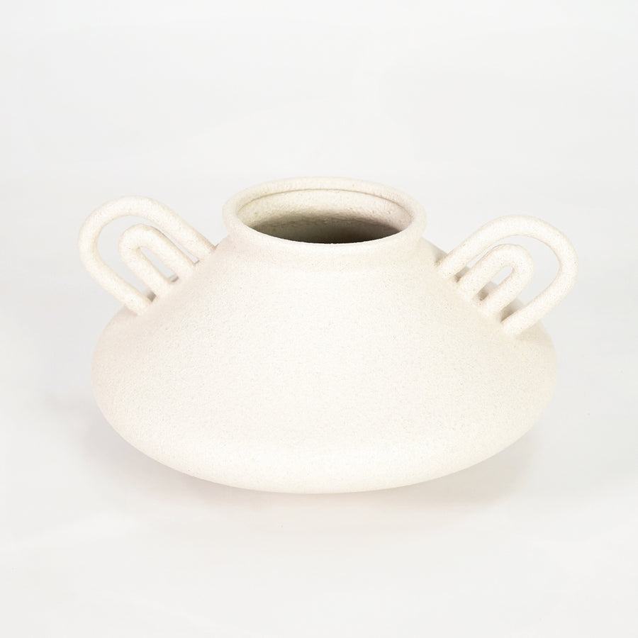 White ceramic vase with loop handles for modern shelf placement and elegant indoor home decor styling accent.