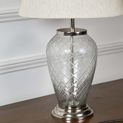 Closeup of glass table lamp with textured glass base and elegant white lampshade – premium home decor lighting.