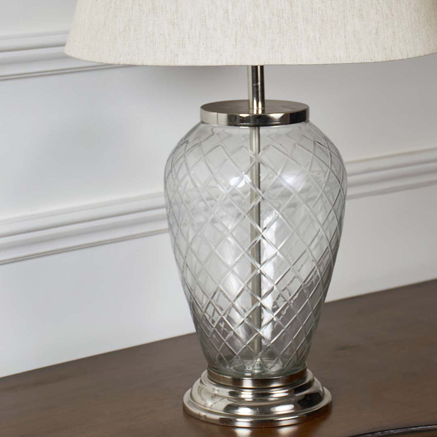 Closeup of glass table lamp with textured glass base and elegant white lampshade – premium home decor lighting.