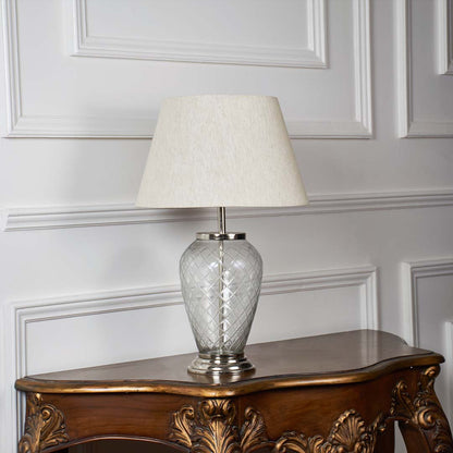 Glass base table lamp with fabric shade on plain white background – light off view.