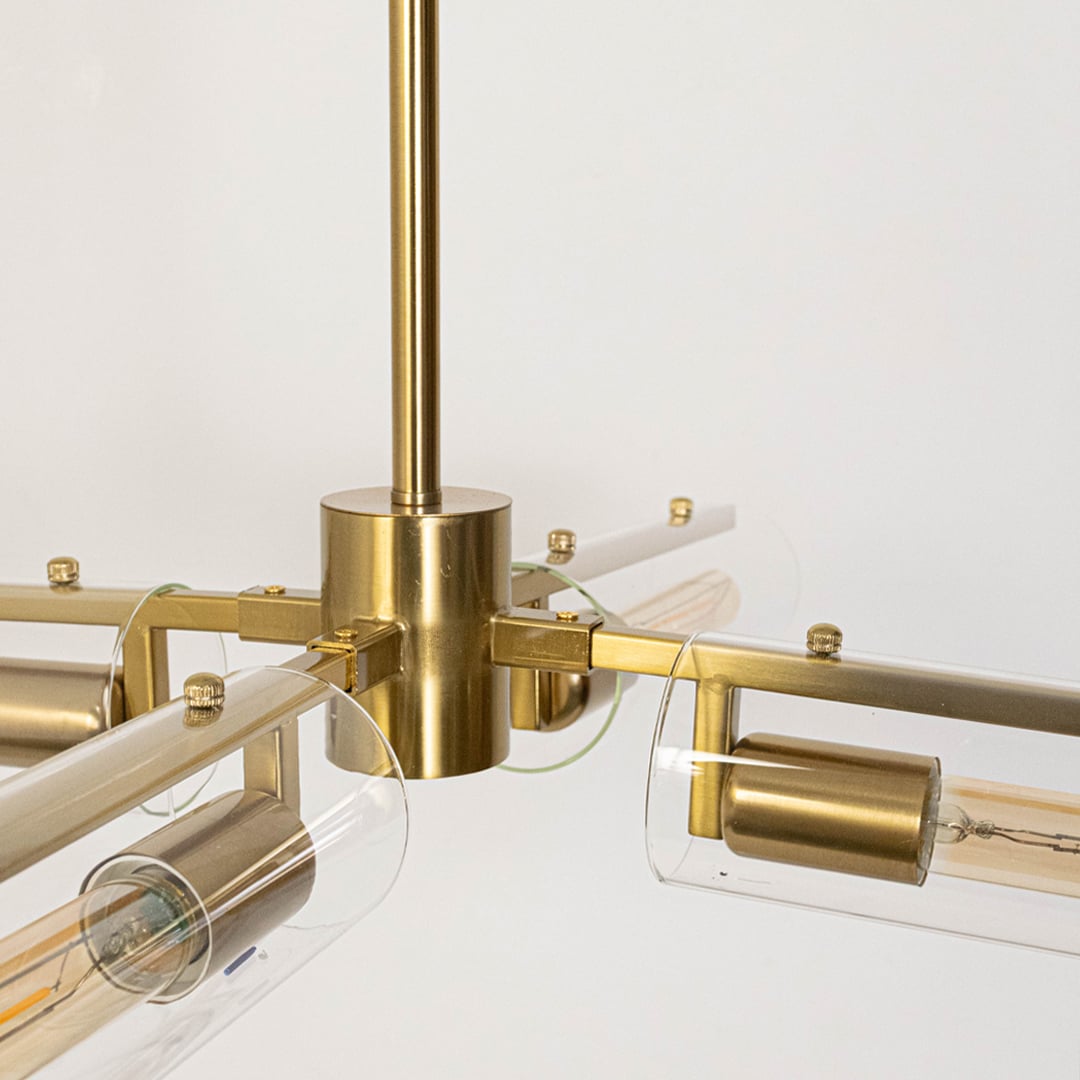 Closeup of gold brass chandelier with exposed filament tubular bulbs showing industrial modern design and craftsmanship detail.