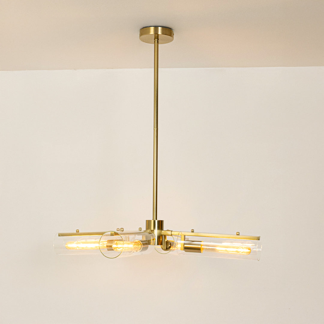 Gold metal chandelier with crystal tube shades creating radiant modern ambient lighting for elegant interior spaces.