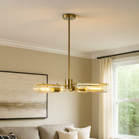 Gold brass chandelier with exposed tubular bulbs creating warm industrial modern lighting in contemporary interior space.