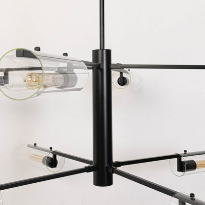 Detailed closeup of clear glass tube shade with exposed Edison bulb and black metal arms on contemporary chandelier fixture.