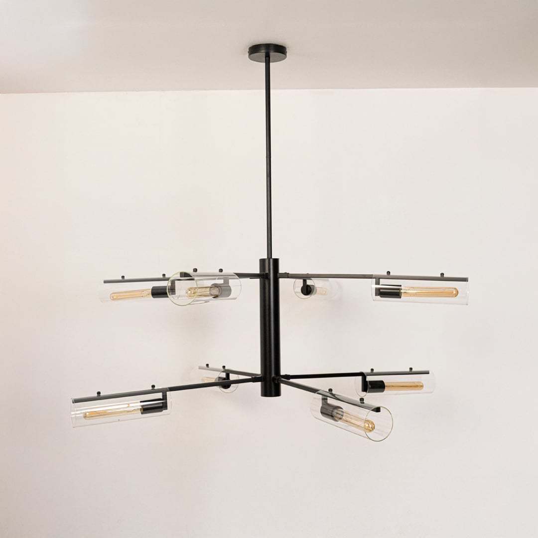 Contemporary black metal multi arm chandelier with clear glass tubular shades turned off displayed on pristine white background.