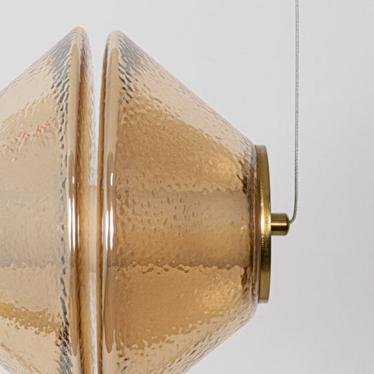 A detailed closeup of a hammered glass pendant light showing the textured glass surface and warm inner glow for an elegant refined look.