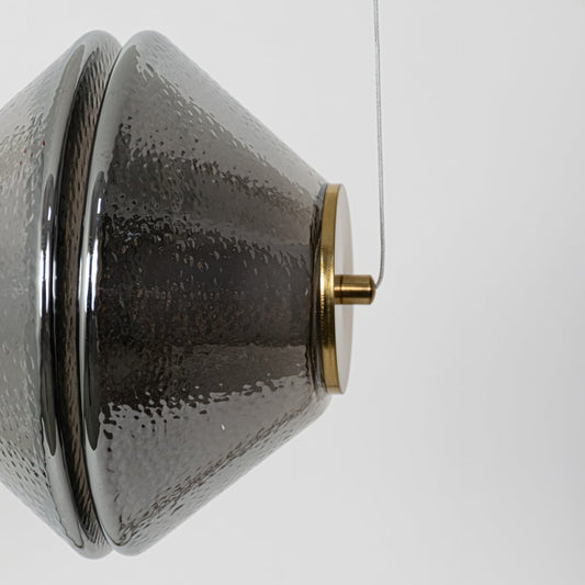 A closeup view of the hammered glass pendant light highlighting the intricate textured surface and warm glow from the inner light.