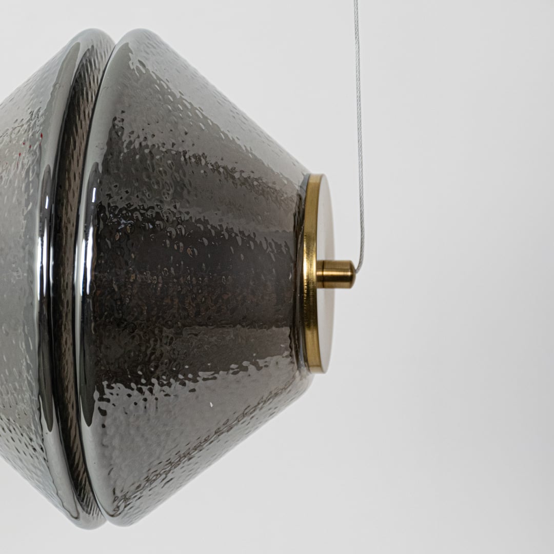 A closeup view of the hammered glass pendant light highlighting the intricate textured surface and warm glow from the inner light.