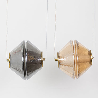 Two textured glass pendant lights shown side by side with the lights on highlighting amber and grey glass tones for a warm balanced glow.