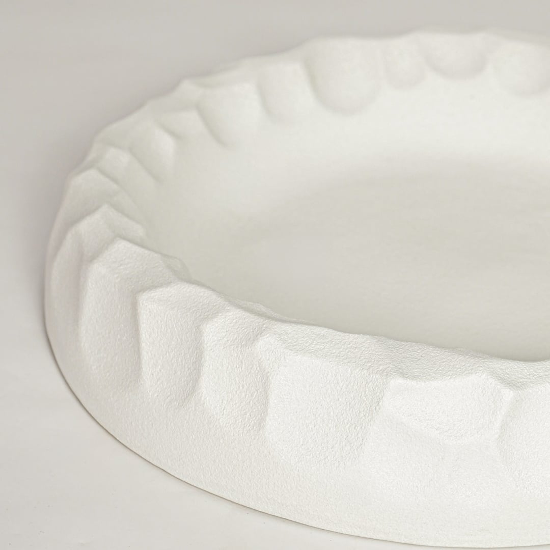 White ceramic decorative bowl with sculpted textured rim perfect for elegant dining table centerpiece and interior decor styling.
