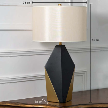 Black and gold geometric table lamp with white drum shade shown with dimensions of 38 cm width 69 cm height and 38 cm depth ideal for side tables or consoles.