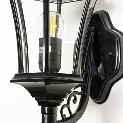Closeup of black metal outdoor wall lantern highlighting clear glass panels bulb holder and solid traditional construction.