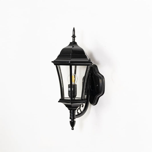 Traditional black metal outdoor wall lantern switched off on white background highlighting classic lantern shape and metal detailing.