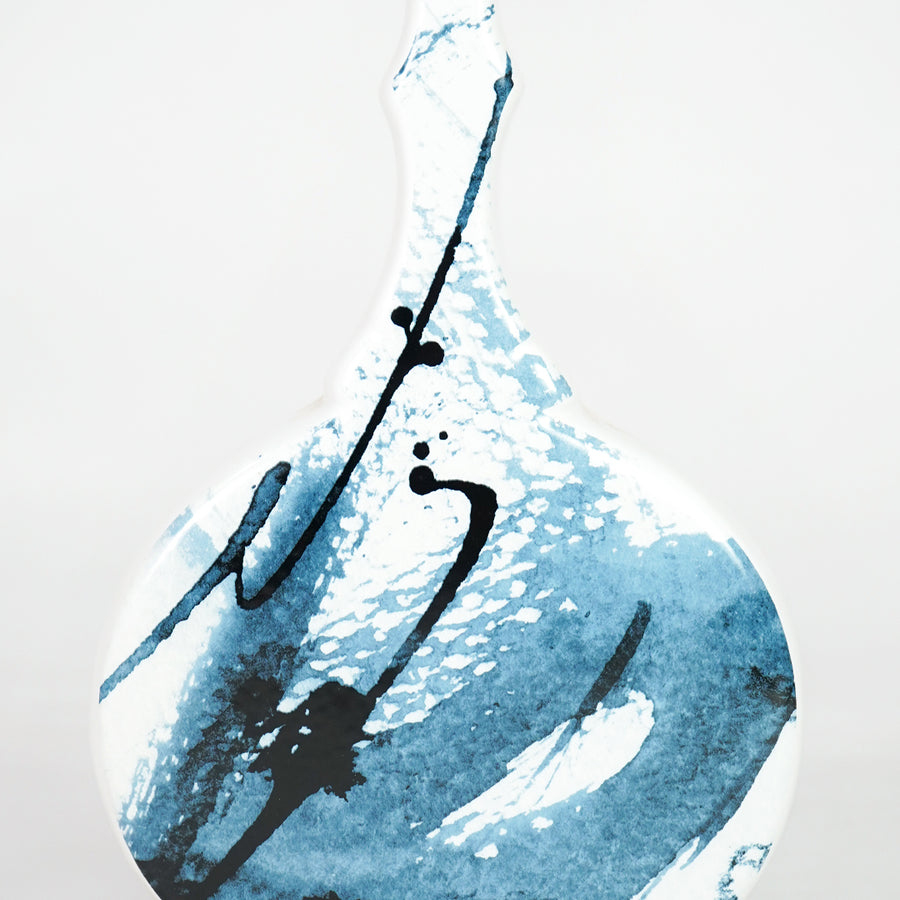 Closeup image of white ceramic artistic vase with blue abstract detailing for modern tabletop decor styling.