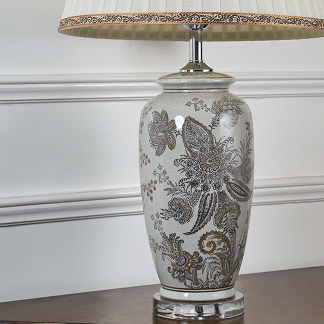 Closeup view of the ceramic lamp showcasing intricate floral patterns and smooth glazed finish with soft light reflecting across the surface.