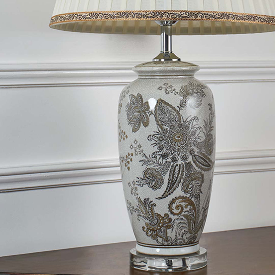 Closeup view of the ceramic lamp showcasing intricate floral patterns and smooth glazed finish with soft light reflecting across the surface.