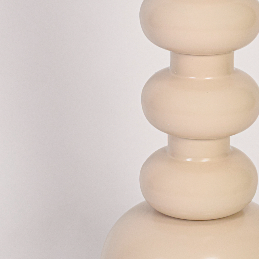 Closeup view of textured fabric shade and smooth stacked lamp stem showing refined finish and elegant craftsmanship under warm lighting.
