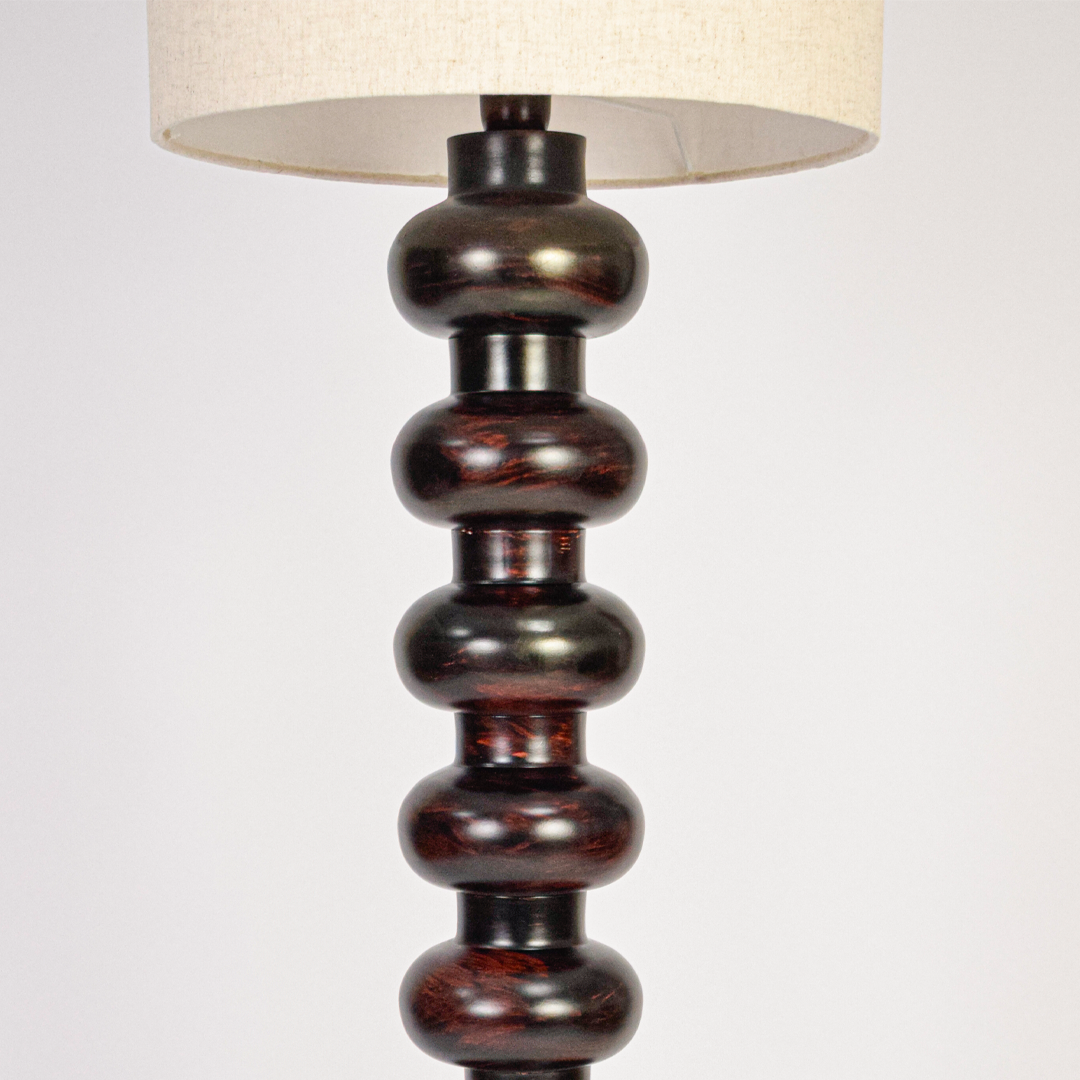 Closeup of floor lamp stacked column base showing smooth curves rich finish and premium craftsmanship with soft light reflecting across surface.