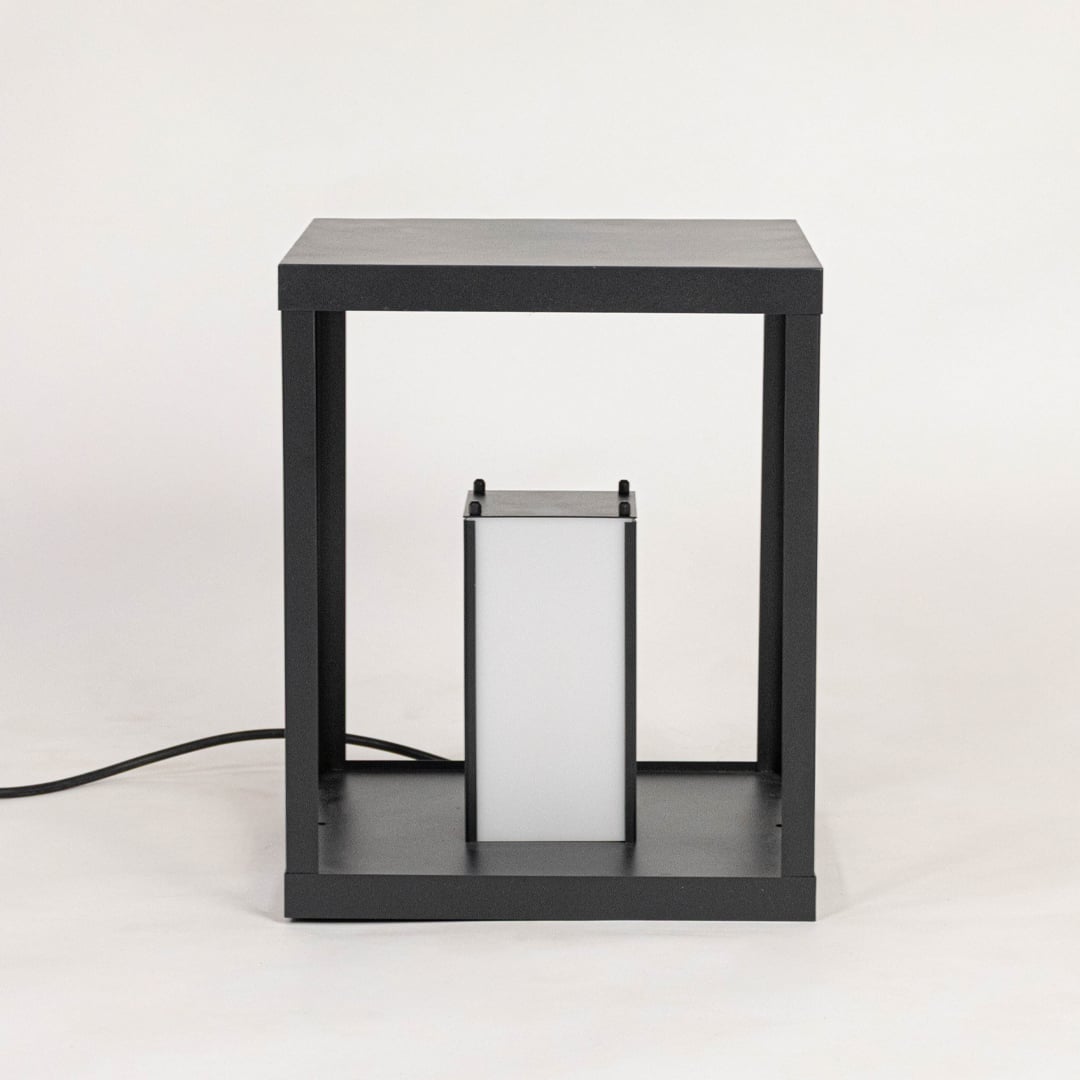 Minimalist table lamp with black frame and frosted white shade displayed off on plain white background.