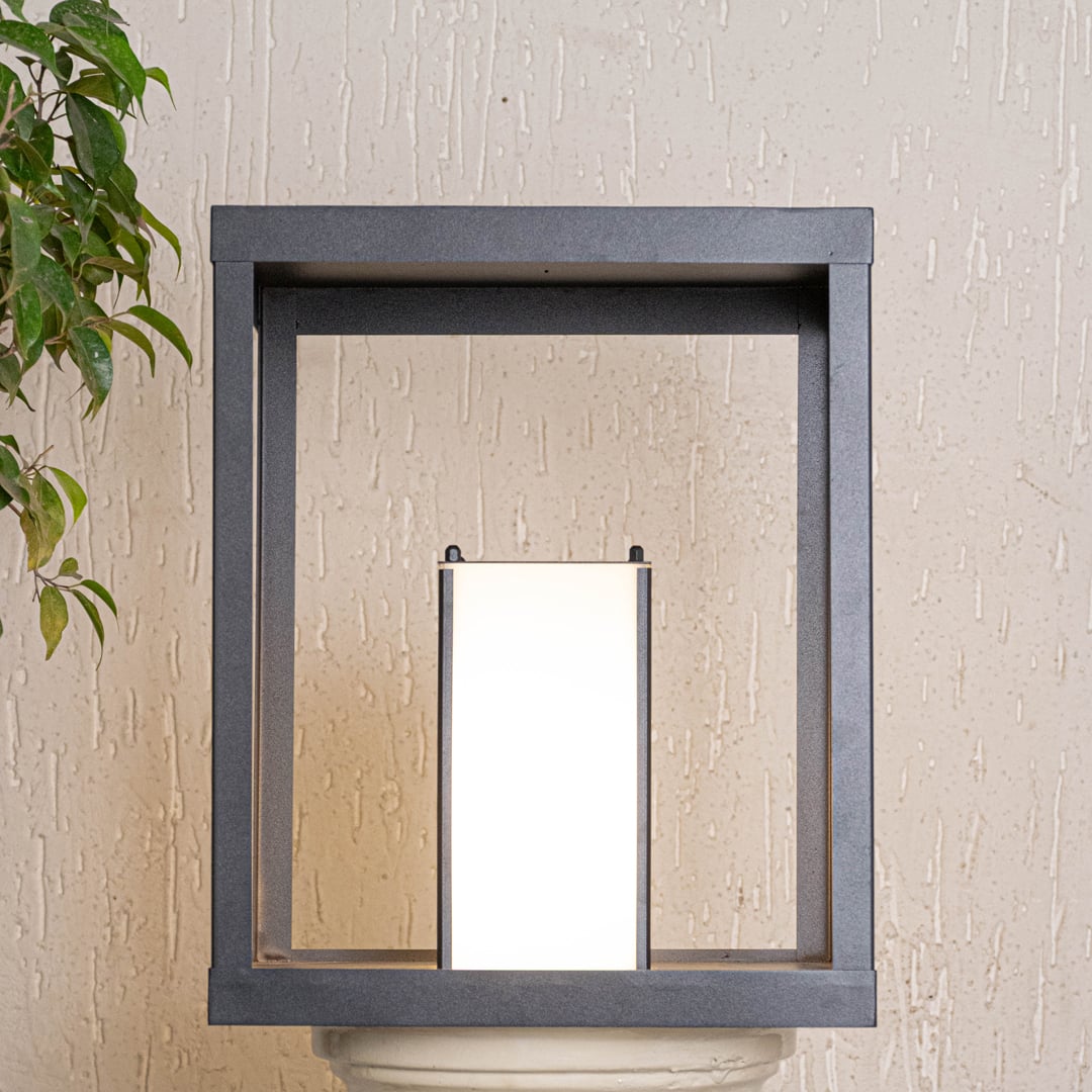 Outdoor gate light illuminated on white background showcasing warm glow metal frame structure and contemporary outdoor wall lighting style.