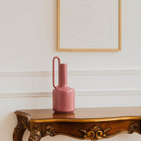 Modern pink ceramic vase with an elongated handle styled in a minimal setting  adding a bold contemporary accent to the decor scene.