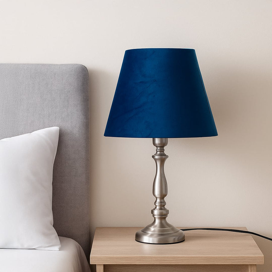 Deep blue velvet lampshade displayed in a warm styled setting showing its rich texture and modern tapered shape in a lifestyle scene.