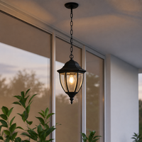 Traditional black iron chain hanging teardrop glass lantern pendant light from porch ceiling for residential patio decor.