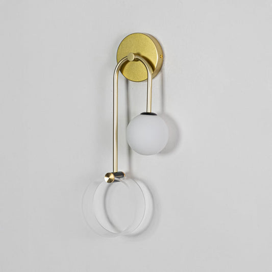A gold wall light with a frosted globe and clear circular rings displayed on a white background with the light off showcasing the fixture structure and refined shape.