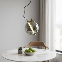 Smoke glass and gold metal pendant light creating warm ambience in contemporary dining interiors.