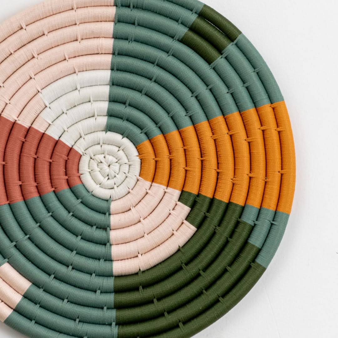 Closeup of handcrafted multicolor seagrass wall basket with green peach white and mustard woven pattern for home décor.